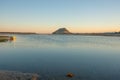 Landmark Mount Maunganui on distant horizon at sunrise with old-fashioned clinker dinghy on beach Royalty Free Stock Photo