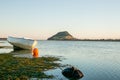 Landmark Mount Maunganui on distant horizon at sunrise with old-fashioned clinker dinghy on beach