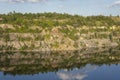 landscape of abandoned granite quarry in summer, in water reflection cloudy sky Royalty Free Stock Photo