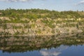 landscape of abandoned granite quarry in summer, in water reflection cloudy sky