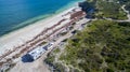 Landscape aerial view of 4WD and modern caravan parked adjacent to a sparkling sunny beach