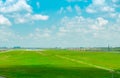 Landscape of the airport runway and green grass field with blue sky and white clouds. Plane on taxiway. Airplane take off at