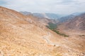 Landscape of the amazing colorful red mountains over the thin curved asphalt road in rocky canyon Royalty Free Stock Photo