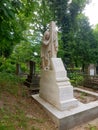 Landscape. An ancient crypt made of stone. The statue of a woman who holds a handkerchief in her hand is displayed, and she herse