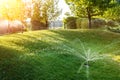 Landscape automatic garden watering system with different sprinklers installed under turf. Landscape design with lawn hills and