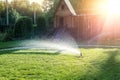 Landscape automatic garden watering system with different sprinklers installed under turf. Landscape design with lawn hills and