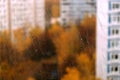 Landscape with autumn in the city view through transparent window glass with focus on rain drops Royalty Free Stock Photo