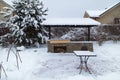 Landscape with barbeque area, snowbanks of white snow, pine trees in country garden.