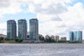 Landscape with bay, three high buildings and sky with white cumulus clouds