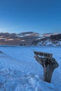 Landscape of the beach area and wooden sign of the Black Sand Beach completely covered with snow with golden light of sunrise