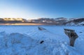 Landscape of the beach area and wooden sign of the Black Sand Beach completely covered with snow with golden light of sunrise