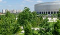 Landscape with beautiful ornamental trees and white facade stadion. Public landscaped city park `Krasnodar` or `Galitsky park`.