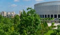 Landscape with beautiful ornamental trees and white facade stadion. Public landscaped city park `Krasnodar` or `Galitsky park`