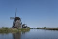 Landscape with beautiful traditional dutch windmills near the water canals with blue sky and clouds reflection in water Royalty Free Stock Photo