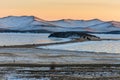 Landscape with beautiful winter frozen lake and snowy mountains at sunset at lake Baikal. Panoramic view