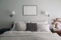 Landscape black picture frame mockup on sage green wall. Elegant bedroom view. White and grey linen pillows, blanket