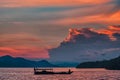 Landscape with a boat floating on the water. On the background of the contour of the shoreline and a fiery sunset. Close up