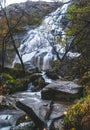 Landscape of cascade Steall Waterfall on wet rocks in autumn in the forest, Scotland Royalty Free Stock Photo