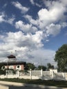 landscape clouds against the sky in the foreground of house trees and white fence Royalty Free Stock Photo