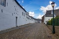 Landscape a cobbled street in white Dutch town of Thorn against blue sky and clouds