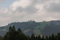 Landscape of dense clouds over high hills, green fields and pine forest in valley Royalty Free Stock Photo