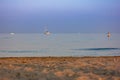 Landscape that depicts a beach with sea and boats at dawn.