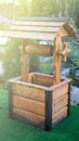 Landscape design with decorative wooden well and a roof in green garden