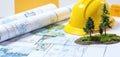 Landscape design plans showing blueprints with a yellow hard hat and miniature trees. Project development involves architectural Royalty Free Stock Photo