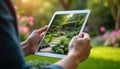 Landscape designer uses tablet for backyard garden planning. Digital visualization modern green layout with stone path, rich Royalty Free Stock Photo
