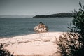 landscape of distant mountains and forest from calm lonely white sand beach next to curious small rock island in calm