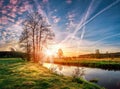 Landscape of early spring at morning sunrise on river. Bright sun lights through trees on horizon. Beautiful spring nature