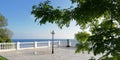 Landscape. The embankment of the seaside town on a sunny summer day through the green leaves of the trees against the blue sky.