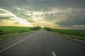 Landscape with empty asphalt road at sunset. Cloudy sky and green meadows Royalty Free Stock Photo