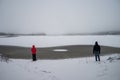 A landscape of an explorer family wearing red jacket in winter wonderland trees covered with white snow and horizon view