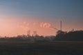 Landscape with field and trees, in the distance factory and a po