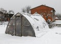 landscape with a film greenhouse, snow on the greenhouse, winter