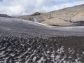 Landscape of Fimmvorduhals hiking trail with close up snow filed covered by black lava ash dunes and volcanic mountains Royalty Free Stock Photo
