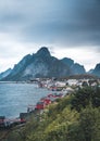 Landscape of fishing village Reine with the Reine Fjord during sunset with nice lights on mountain, blue sky and clouds