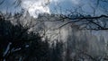 Landscape of fog flowing over mountain forest covered with snow. Winter landscape, cold weather, blizzard and storm Royalty Free Stock Photo