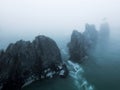 A landscape with fog, pointed cliffs in blue water in cloudy weather in the morning Royalty Free Stock Photo