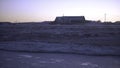 Landscape of frozen field with house on horizon in morning. Clip. Cold dark landscape of snowy field and old barn on Royalty Free Stock Photo