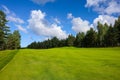 Landscape, golf course,, green grass on the background of a forest and a bright sky with clouds Royalty Free Stock Photo