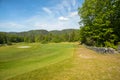 Landscape on a golf course with green grass, trees, beautiful blue sky and stone fence Royalty Free Stock Photo