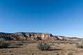 Landscape of grass, sagebrush, and colorful cliffs under a vast blue sky in a high desert landscape in New Mexico
