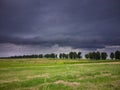 landscape green field with black storm clouds, Storm dark clouds over the field with grass, a storm is coming Royalty Free Stock Photo