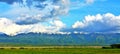 Landscape of green fields with snow-capped peaks mountains in Calimani, Romania Royalty Free Stock Photo