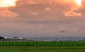 Landscape of green grass field and fence of the airport and beautiful sunset sky. Commercial airplane parked at apron of airport.