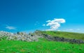 Landscape of green grass and rock mountain in spring with beautiful blue sky and white clouds. Countryside or rural view. Royalty Free Stock Photo