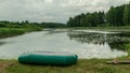 Landscape with green rubber boat on the lake shore, fishing concept, leisure time in nature, summer Royalty Free Stock Photo