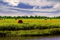 Landscape with haystacks on a field by a river, a strip of forest and blue sky Royalty Free Stock Photo